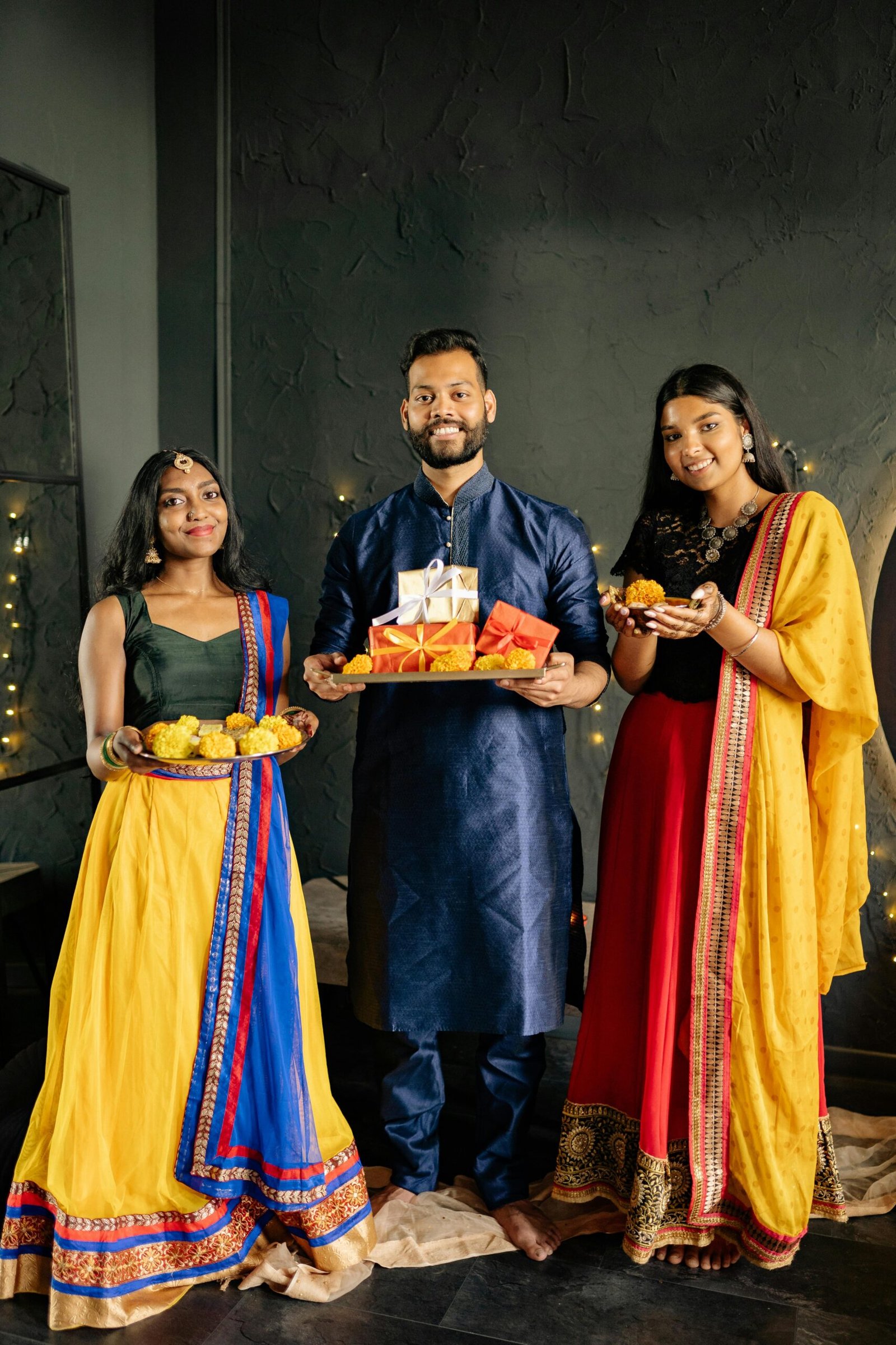 Family wearing traditional clothes celebrates Diwali indoors with gifts and sweets.